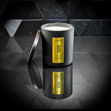 Load image into Gallery viewer, A sleek black candle jar labeled “Ocean Breeze” with a reflective gold foil label, displayed on a glossy black tiled surface. The candle lid is propped open, revealing the white wax inside, and the label reads “Kandie’s Scents, LLC” with minimalistic luxury branding.