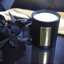 Load image into Gallery viewer, Hand-poured Linen Daze candle in matte black glass jar filled with creamy soy wax, styled with black eucalyptus and gold fabric for a soft luxury look.