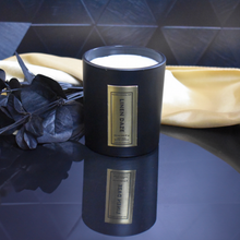 Load image into Gallery viewer, Hand-poured Linen Daze candle in matte black glass jar filled with creamy soy wax, styled with black eucalyptus and gold fabric for a soft luxury look.