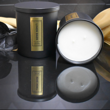 Load image into Gallery viewer, Set of two Linen Daze candles in matte black jars, one upright and one lying on its side to reveal the triple wooden wick and smooth soy wax surface.