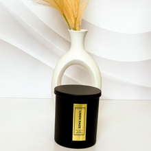Load image into Gallery viewer, Stylish Linen Daze candle in a black matte jar with gold foil label, paired with a modern white vase and peach-toned dried florals for a clean aesthetic.