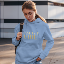 Load image into Gallery viewer, Woman wearing a blue hoodie with 'I AM THE VIBE' text, standing outdoors.
