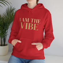 Load image into Gallery viewer, Person wearing a red hoodie with 'I AM THE VIBE' text, standing indoors with a plant in the background.
