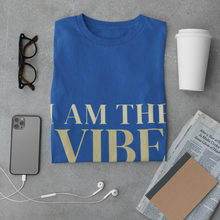 Load image into Gallery viewer, Blue t-shirt with 'I AM THE VIBE' text on a gray surface with phone, coffee, and glasses.
