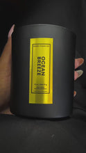 Load and play video in Gallery viewer, A slow-turn video of the 12 oz Ocean Breeze candle, cradled in one hand. The matte black jar with its tall, vertical gold foil label shimmers as it’s rotated, revealing the sleek, upscale branding of Kandie’s Scents. This premium candle embodies bold simplicity and timeless luxury.
